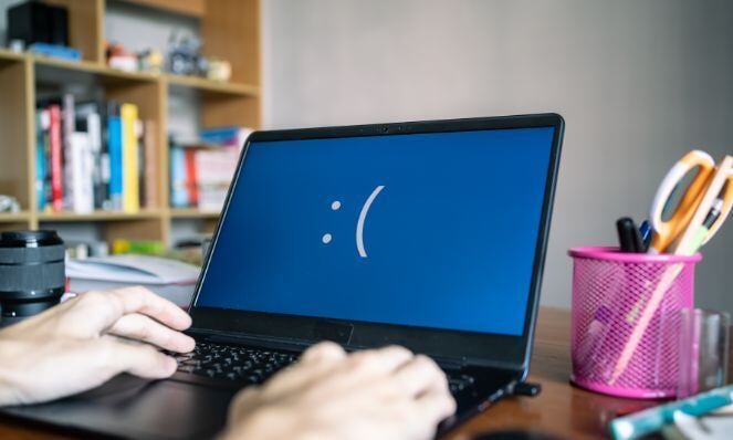 A laptop with blue screen and sad face.