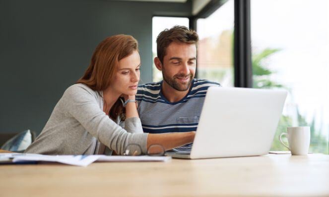 Two people working on one laptop.