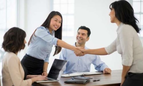 Two lady wearing formal attire having handshake