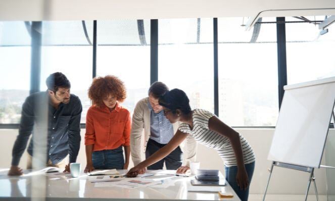 People working together looking at the same time at the paper at the desk.
