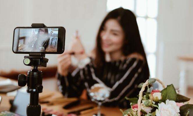 Woman shooting a video of herself doing a tutorial using her mobile phone on a tripod.