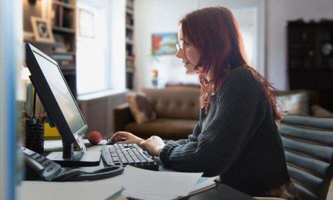 Woman working on her laptop while seated at a desk.