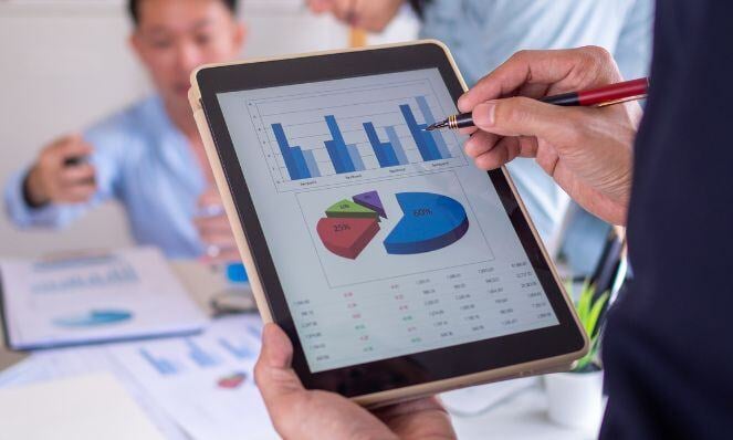 Person holding a tablet with pie chart data.