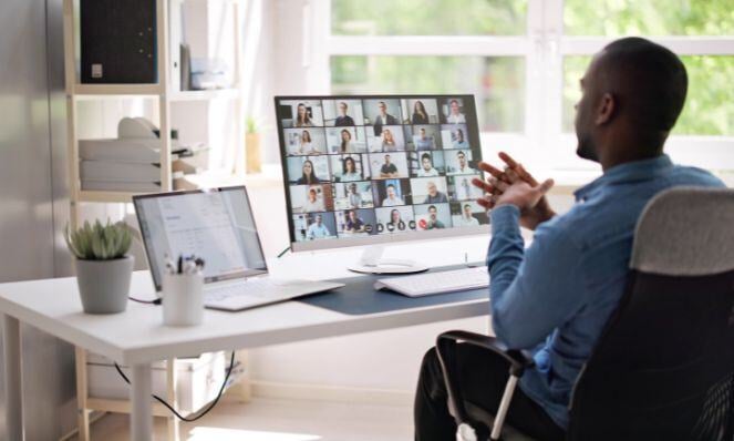 Man seated at a desk while holding an online meeting.
