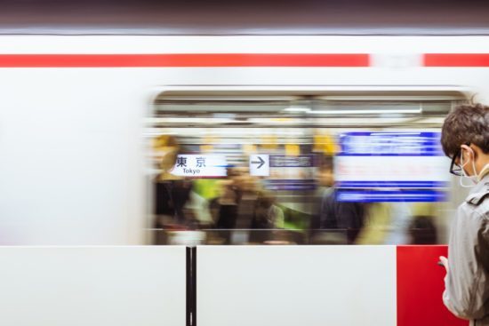 Man glancing at his phone while a subway train speeds by him