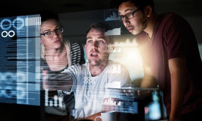 Workmates analyzing data as seen on the screen in front of them.