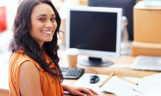 Woman working at her desk while smiling.