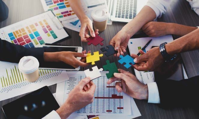 People holding a puzzle pieces and putting it together.