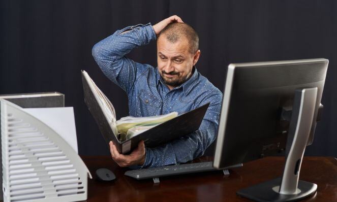 A man is looking frustrated while looking at the files.
