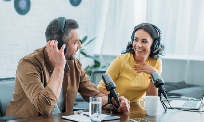 Woman and man talking on microphone while wearing headsets.