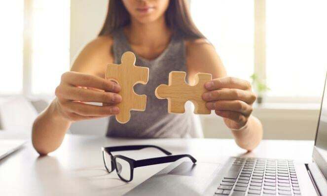 Woman piecing large puzzle pieces together.