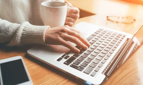 typing on a laptop with coffee