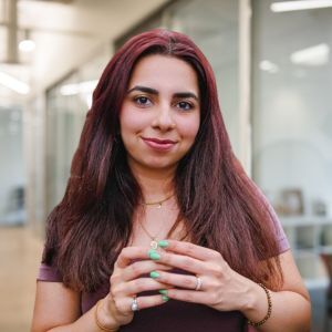 Photo of Puja Vaz in a corporate office setting. She is smiling at the camera.